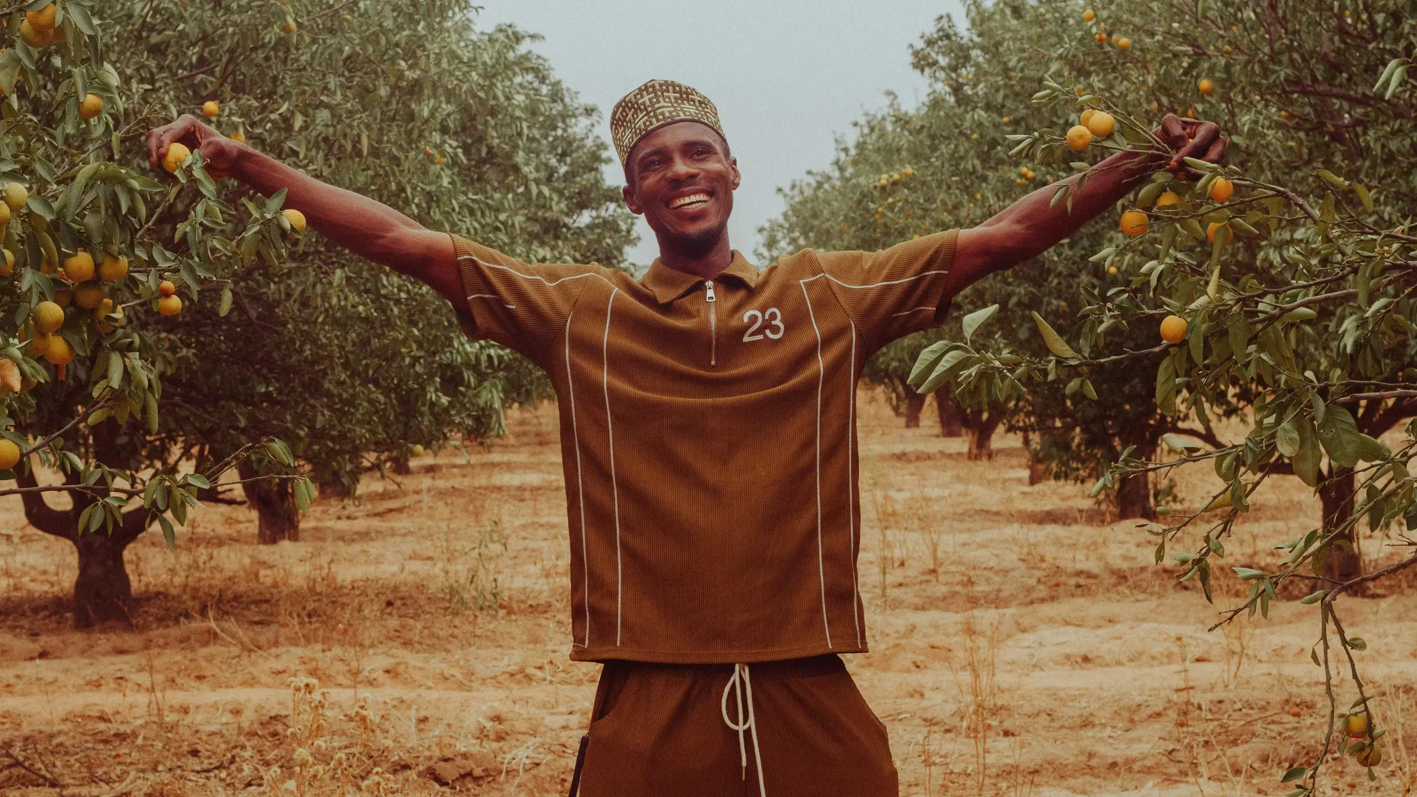 A young man between trees with fruits on them